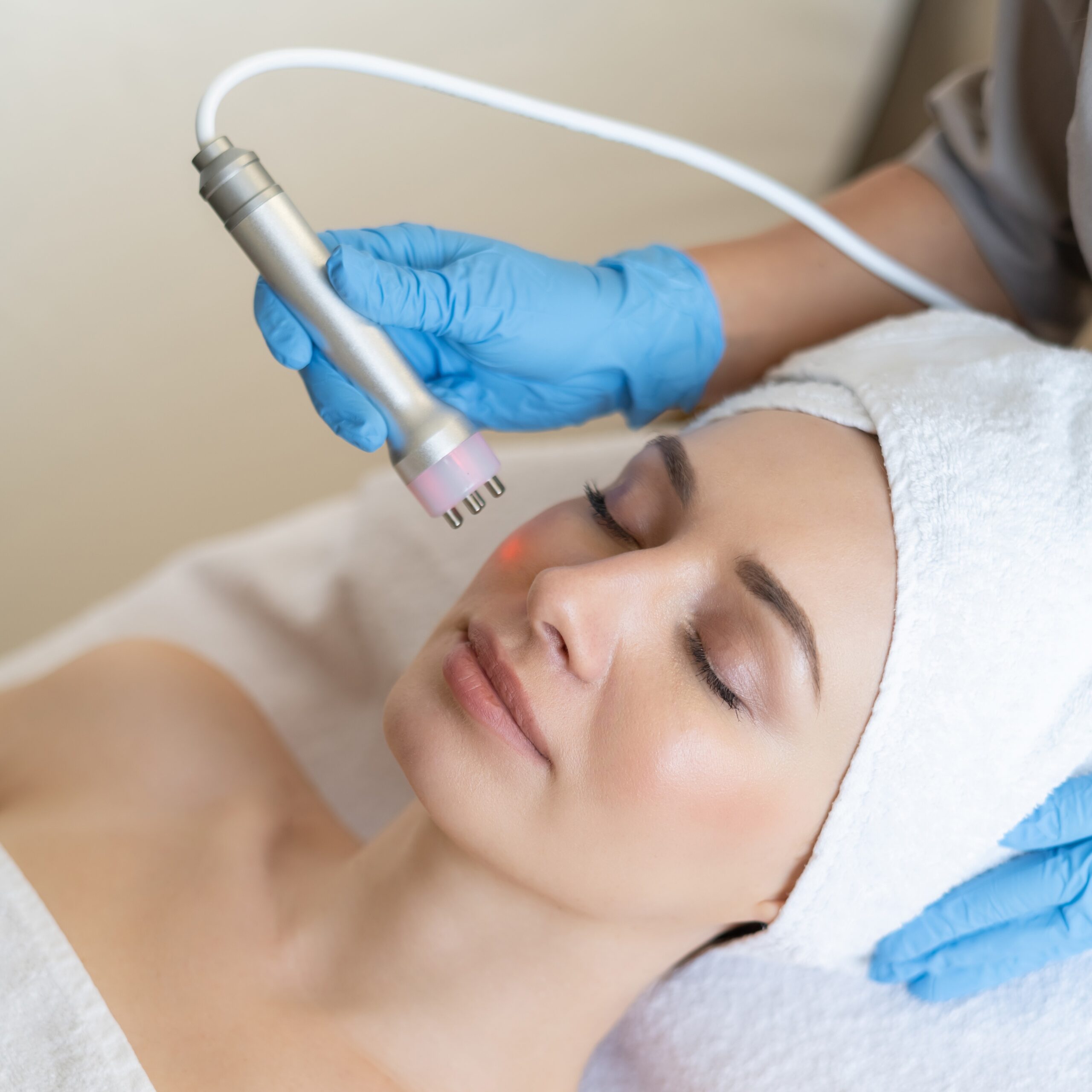 Radiofrecuencia facial mujer joven acostada en la mesa de la cosmetologa durante el procedimiento de radiofrecuencia facial